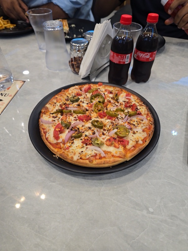 A loaded pizza served with cold drinks